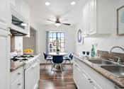 Thumbnail 14 of 28 - a kitchen with white cabinetry and a white stove top oven next to a white table with