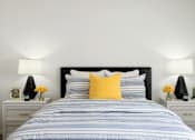 Thumbnail 9 of 28 - a bedroom with a bed and two night stands with lamps on them