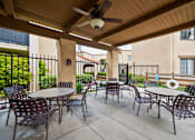 Thumbnail 24 of 28 - an outdoor patio with tables and chairs and a ceiling fan