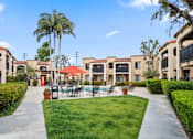 Thumbnail 20 of 28 - a courtyard with tables and chairs and a pool with palm trees in the background