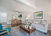 Thumbnail 2 of 29 - a living room with a couch coffee table and chairs and a dining room table in the background