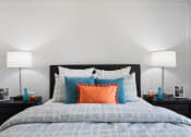 Thumbnail 10 of 40 - a bedroom with a bed with blue and orange pillows and two lamps