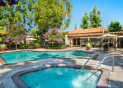 Thumbnail 21 of 40 - a swimming pool with a hot tub and a resort style building in the background