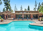 Thumbnail 29 of 37 - A large swimming pool in front of a building with a covered patio area.