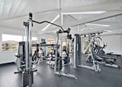 Thumbnail 29 of 36 - A gym with a variety of equipment including a weight machine, a treadmill, and a stationary bike.