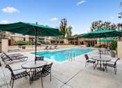 Thumbnail 32 of 36 - A pool area with tables and chairs and umbrellas.