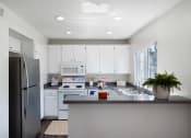 Thumbnail 26 of 38 - a kitchen with white cabinets and stainless steel appliances and a counter top