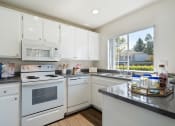 Thumbnail 25 of 38 - a kitchen with white appliances and granite counter tops