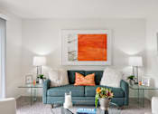 Thumbnail 3 of 49 - a living room with a blue couch and a orange painting on the wall