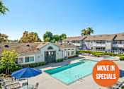 Thumbnail 2 of 68 - A pool surrounded by chairs and umbrellas with a sign that says "Move in Specials".
