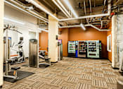 Thumbnail 18 of 24 - A gym with orange walls and a variety of equipment.