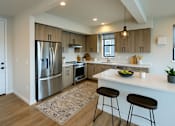 Thumbnail 21 of 24 - A modern kitchen with a white countertop and stainless steel appliances.