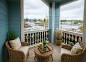 Thumbnail 24 of 24 - A balcony with a wicker chair, a sofa, a table and a potted plant.
