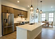 Thumbnail 7 of 24 - A modern kitchen with a large island and stainless steel appliances.