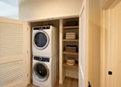 Thumbnail 12 of 24 - A washing machine is in a cabinet in a room.