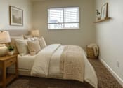 Thumbnail 1 of 16 - A bedroom with a bed, nightstand, and window.