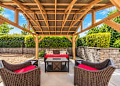 Thumbnail 9 of 21 - A wooden pergola with a table and chairs underneath it.