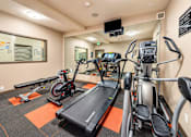 Thumbnail 13 of 21 - A gym with treadmills, exercise bikes, and a television.
