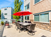 Thumbnail 10 of 21 - A patio with a table and chairs and an umbrella.