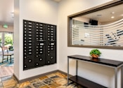 Thumbnail 15 of 21 - A black mailbox with white numbers is on the wall next to a desk with a potted plant on it.