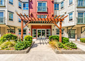 Thumbnail 14 of 21 - A building with a red door and a wooden pergola in front.