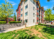 Thumbnail 20 of 21 - A multi-story apartment building with a red and beige exterior.