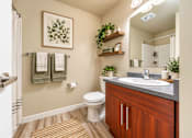 Thumbnail 7 of 21 - A bathroom with a toilet, sink, and a mirror.