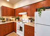 Thumbnail 4 of 21 - A kitchen with wooden cabinets and a white refrigerator.