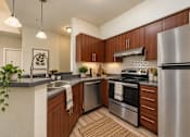 Thumbnail 1 of 21 - A modern kitchen with wooden cabinets and stainless steel appliances.