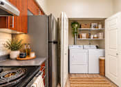 Thumbnail 3 of 21 - A kitchen with a refrigerator, oven, and a small potted plant on the counter.
