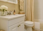 Thumbnail 3 of 15 - A white bathroom with a toilet, sink, and shower.