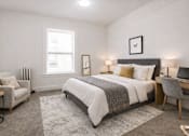 Thumbnail 6 of 24 - A bedroom with a large bed, a chair, and a desk.