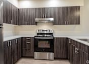 Thumbnail 15 of 24 - A modern kitchen with dark wood cabinets and stainless steel appliances.
