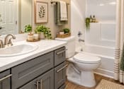 Thumbnail 7 of 13 - A white toilet sits in a bathroom next to a bathtub.