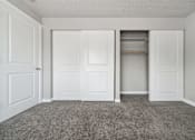 Thumbnail 16 of 20 - A room with white doors and a carpeted floor.