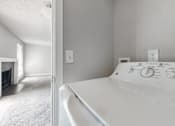 Thumbnail 13 of 20 - A white washing machine in a room with a fireplace.