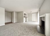 Thumbnail 8 of 20 - A spacious living room with a fireplace and carpeted floor.