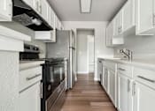 Thumbnail 10 of 20 - A kitchen with white cabinets and black appliances.