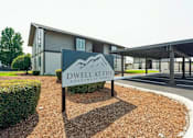Thumbnail 20 of 20 - A sign for Dwell at Life Apartment Homes stands in front of a modern building.