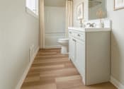 Thumbnail 11 of 20 - A bathroom with a white vanity and a walk-in shower.