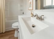Thumbnail 12 of 20 - A white bathroom with a toilet, sink, and shower.