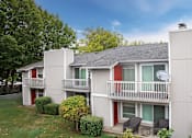 Thumbnail 1 of 13 - A small white house with a red door and a balcony.