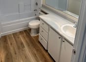 Thumbnail 12 of 16 - A white bathroom with a toilet, sink, and mirror.