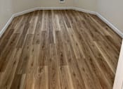 Thumbnail 9 of 16 - A room with wooden flooring and white walls.