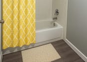 Thumbnail 9 of 21 - A yellow shower curtain with a diamond pattern hangs in a white bathroom.