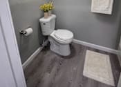 Thumbnail 10 of 21 - A small bathroom with a toilet, a flower pot, and a towel.