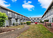 Thumbnail 2 of 21 - A row of grey apartment buildings with a walkway in the middle.