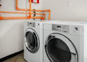 Thumbnail 18 of 21 - Two front load washing machines in a laundry room.