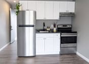 Thumbnail 3 of 21 - A modern kitchen with a stainless steel refrigerator and white cabinets.