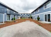 Thumbnail 19 of 21 - A long concrete driveway leads between two rows of identical houses.